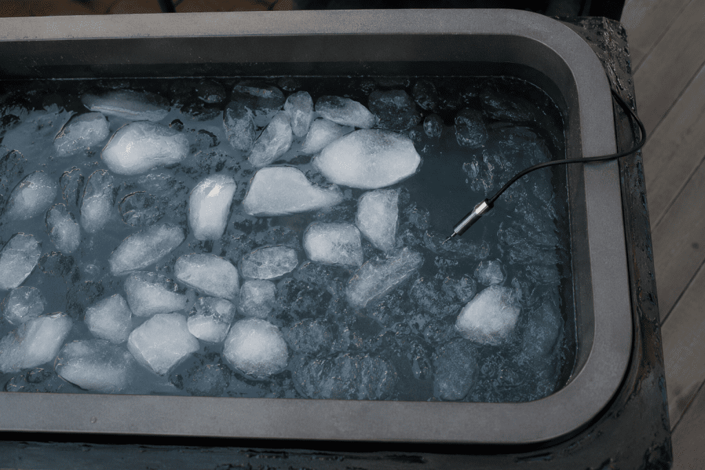 cold plunge safety - ice cubes floating in a cold water tub with a thermometer probe visible