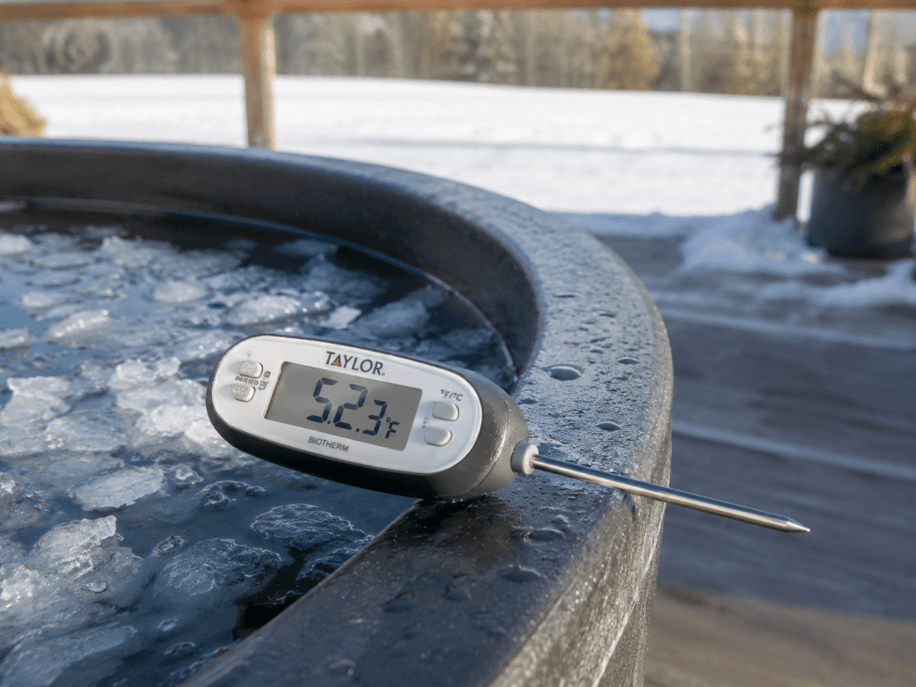 digital thermometer resting on the edge of a cold plunge tub outdoors sign of hypothermia in ice baths