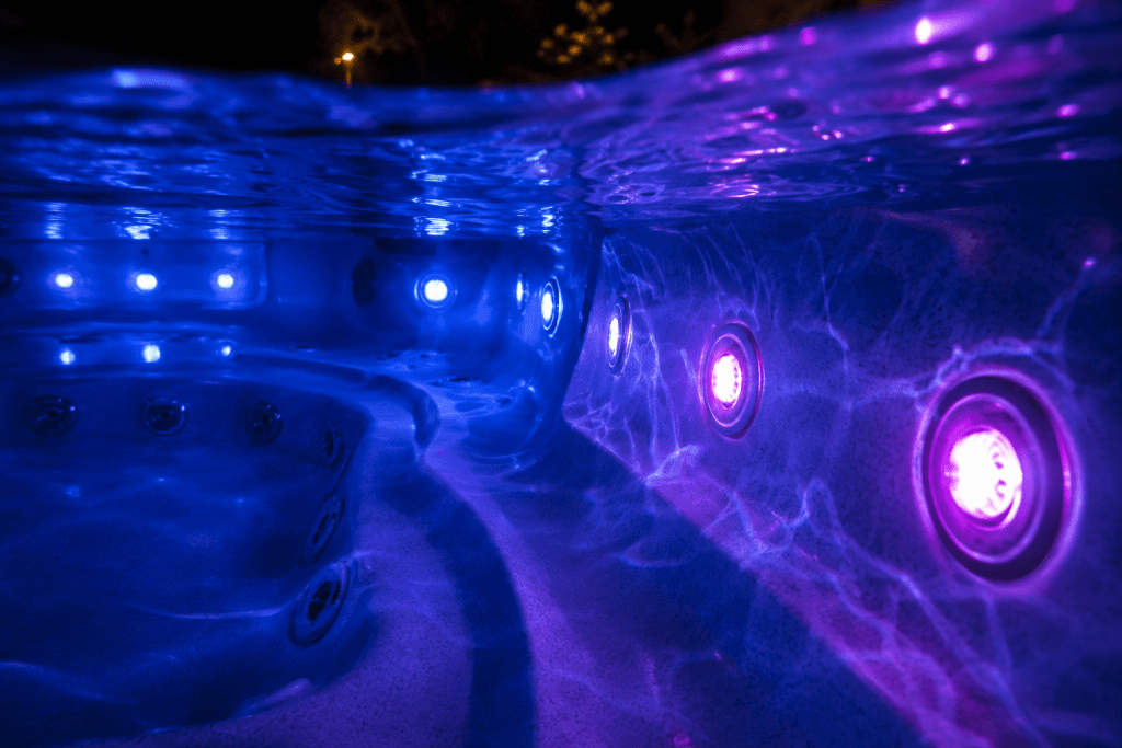  underwater LED lights glowing blue and purple in an outdoor hot tub at night